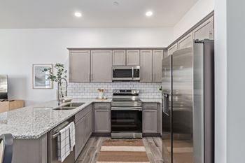 A modern kitchen with a granite countertop and stainless steel appliances.